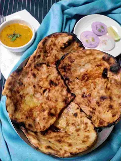 Serving amritsari kulcha in a bread basket dal and onion slices in background