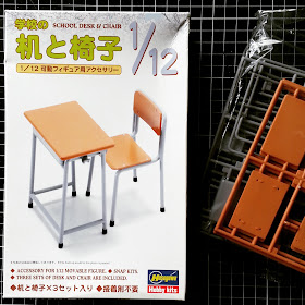 Pieces of a 1/12 scale kit for a school desk and chair next to the box they came in.