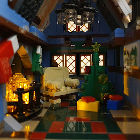A room recreated in LEGO, with a lit up fireplace, Christmas tree with presents and an empty chair. 