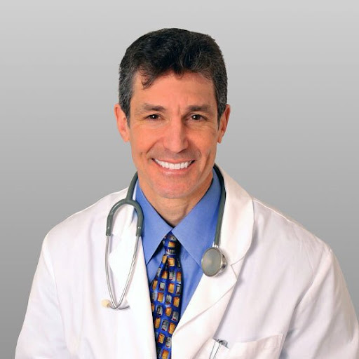 O Dr. Katz balançando um jaleco branco engomado e um estetoscópio no pescoço com um sorriso radiante