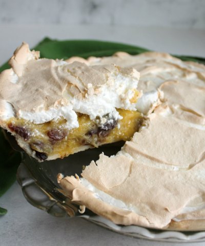 If this sour cream and raisin pie tastes like something your grandma would make, it's because she probably would! This pie is sweet, creamy and delicious with a pillow of fluffy meringue on top. first slice of meringue topped sour cream and raisin pie being lifted out of the pan