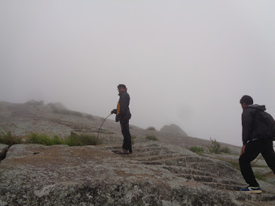 Ashok navigates the rock face with steps with fog engulfing the entire hillock
