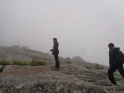 Ashok navigates the rock face with steps with fog engulfing the entire hillock