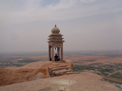 Hiker sitting at the manatap which marks the end of the madakasira trek