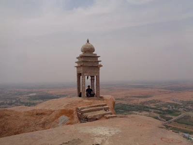 Hiker sitting at the manatap which marks the end of the madakasira trek