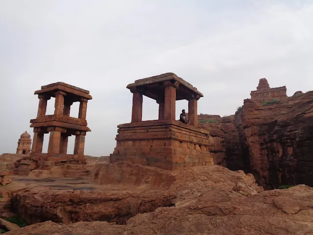 Madhu sitting at the Badami temple complex, admiring the sunrise over the ancient structures