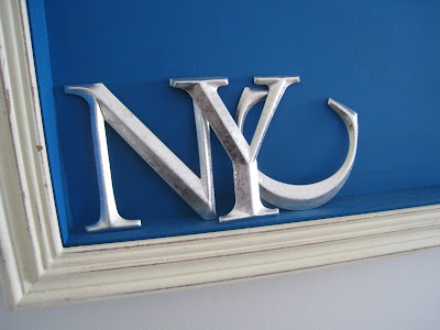 Silver letters in a shadow box made by Shannon Cockrell hung on a wall in her London flat