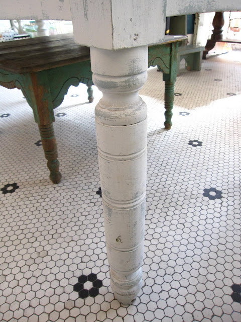 Details of the carved turned leg on a long, white vintage 19th century farmhouse table