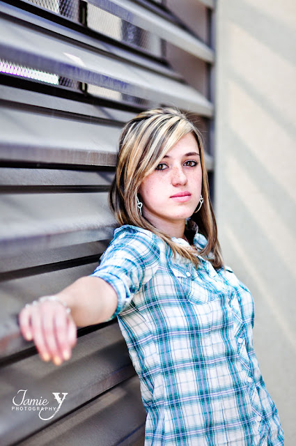 Senior portrait taken at town square in las vegas. Blonde girl leaning up against a cool metal background with awesome rays of light shining through. Taken by JamieY Photography