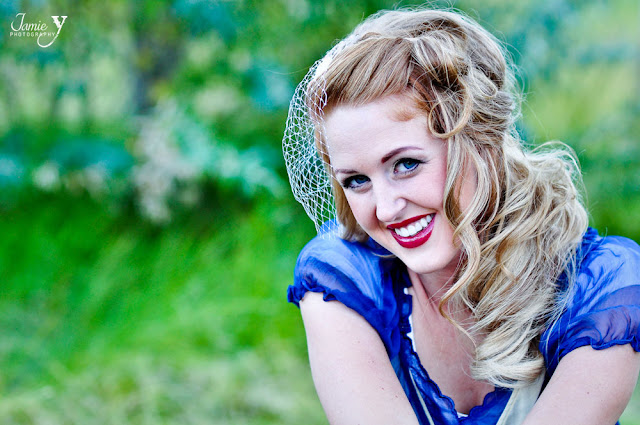 Beautiful girl engagement photography of girl wearing vintage dress and head piece smiling with dark red lipstick taken outside at red rock in las vegas