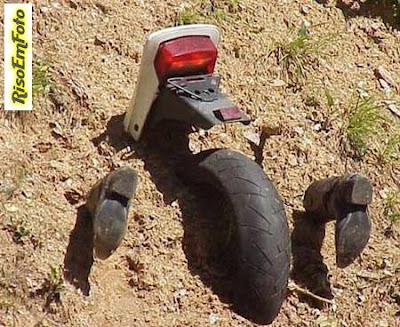 Foto com motocicleta e botas enterradas em monte de terra simula acidente de moto.