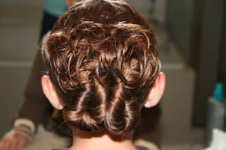 Young girl's hair being styled into "Pretzel-Twist Messy Bun"