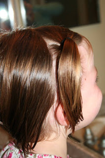 Side view of young girl's hair being styled into "Two Messy Twists on Top" Hairstyle