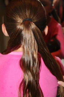 Back view of young girl's hair being styled into "Triple-Twist Ponytail' hairstyle