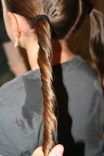 Side view of young girl's hair being styled into "Basic Twisty Buns" hairstyle