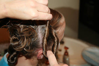 Side view of young girl's hair being styled into "4 Messy-Pigtail Twists" hairstyle