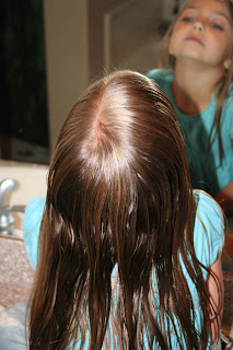 Back view of young girl's hair being styled into "Wrap-Around French Braid" hairstyle