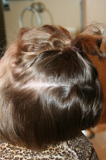 side view of young girl's hair being styled into 3-barrel curl hairstyle on her a-line bob