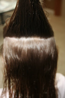 Back view of young girl's hair being styled into "The Bun-Hawk" hairstyle