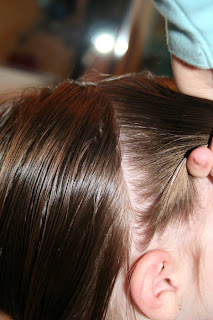 Side view of young girl's hair being styled into "twisty buns" hairstyle