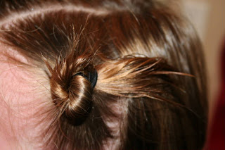 Close up view of young girl's hair being styled into "twisty buns" hairstyle