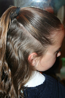 Side view of young girl's hair being styled into "Best Three-Leaf Clover" hairstyle