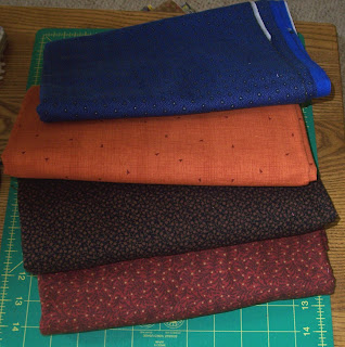 red, black, orange & blue fabrics for mystery quilt