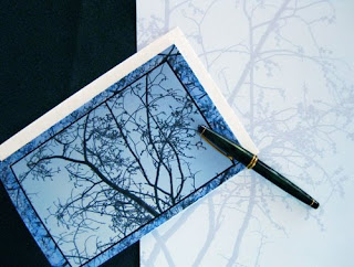 A display of a greeting card of delicate budding tree branches against a field of blue sky.