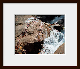 Rivulets of water cascade over a russet colored rock in coppery streams of color. Rocky Mountain National Park, Colorado