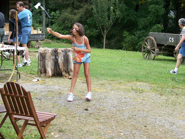 A young visitor learns how to throw a tomahawk