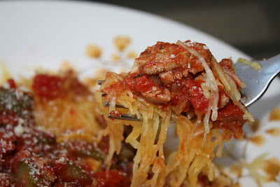 bowl of spaghetti squash shreds with ground turkey and parmesan cheese covered in vegetable ragu red sauce, fork picking up a piece from the bowl