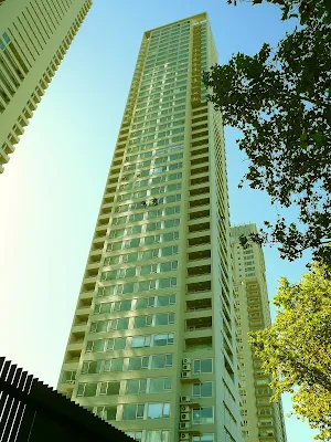 Un edificio gigante de departamento con dos personas trabajando en altura.