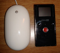 Apple mouse sitting beside a Flip Mino HD