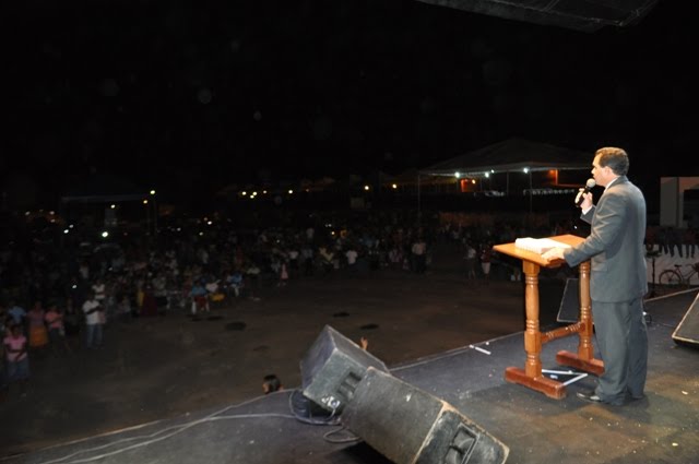 Pastor orando, ao fundo o público.