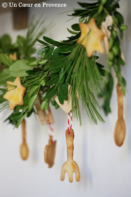 Guirlande faite de branches de sapin, buis, cade, romarin et décorée de sablés en forme de cuillère, fourchette et étoile