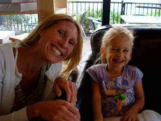 Woman leaning over chair smiling with young girl