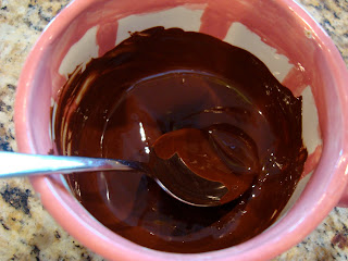 Melted chocolate in pink and white bowl with spoon stirring