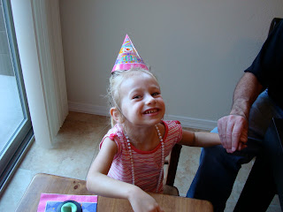 Young girl wearing birthday hat and necklace