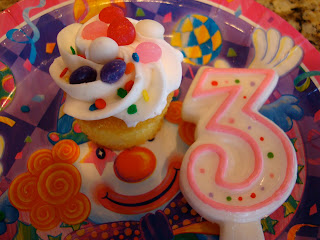 Decorated cupcake on plate with a large number three candle