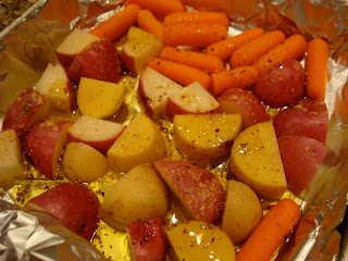 Foil lined pan of diced potatoes and carrots in olive oil and seasonings