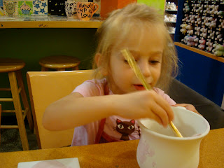 Young girl painting pottery mug