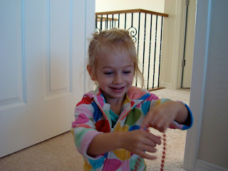 Young girl playing with red string of beads