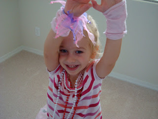 Young girl playing dress up with arms up in air
