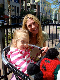 Woman kneeling beside seated child smiling outside coffee shop