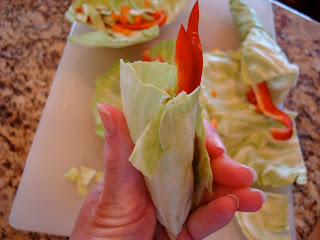 Hand holding cabbage with vegetables rolled up