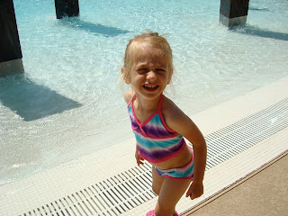 Young girl in bathing suit standing outside of pool