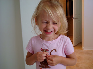 Smiling young girl wearing and holding necklace
