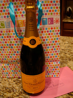 Bottle of champagne in front of gift bag