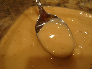 Blended banana mixture in clear container with spoon holding some of mixture