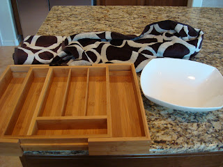 bamboo expandable silverware drawer organizer, white bowl and black and white towel on countertop